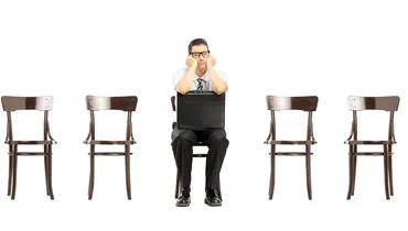 job seeker sitting alone in a line of chairs waiting for an interview