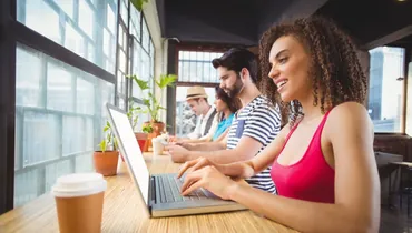 happy friends using electronic devices to help them write their linkedin profiles at a coffee shop